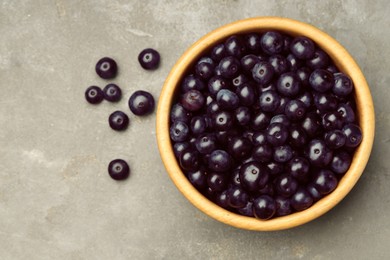 Photo of Ripe acai berries in bowl on grey textured table, top view. Space for text