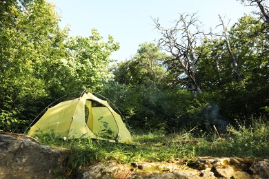 Photo of Modern camping tent in forest at summer, space for text