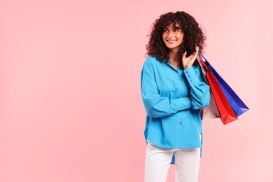 Photo of Smiling woman with colorful shopping bags on pink background. Space for text