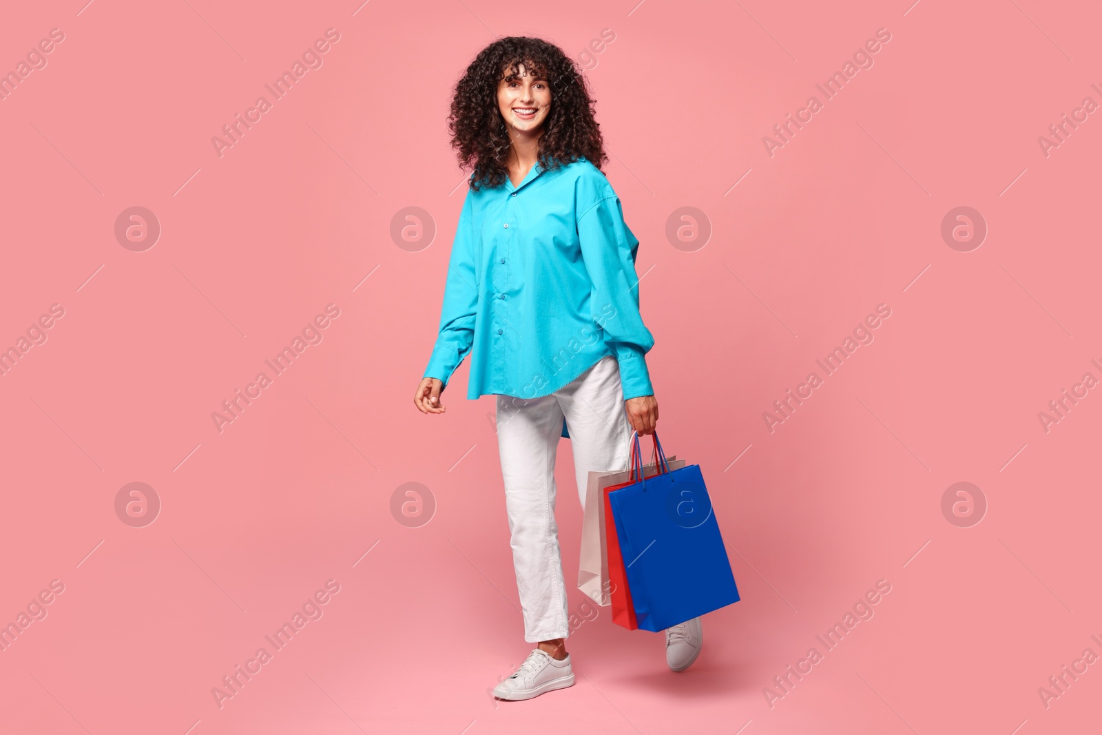 Photo of Smiling woman with colorful shopping bags on pink background