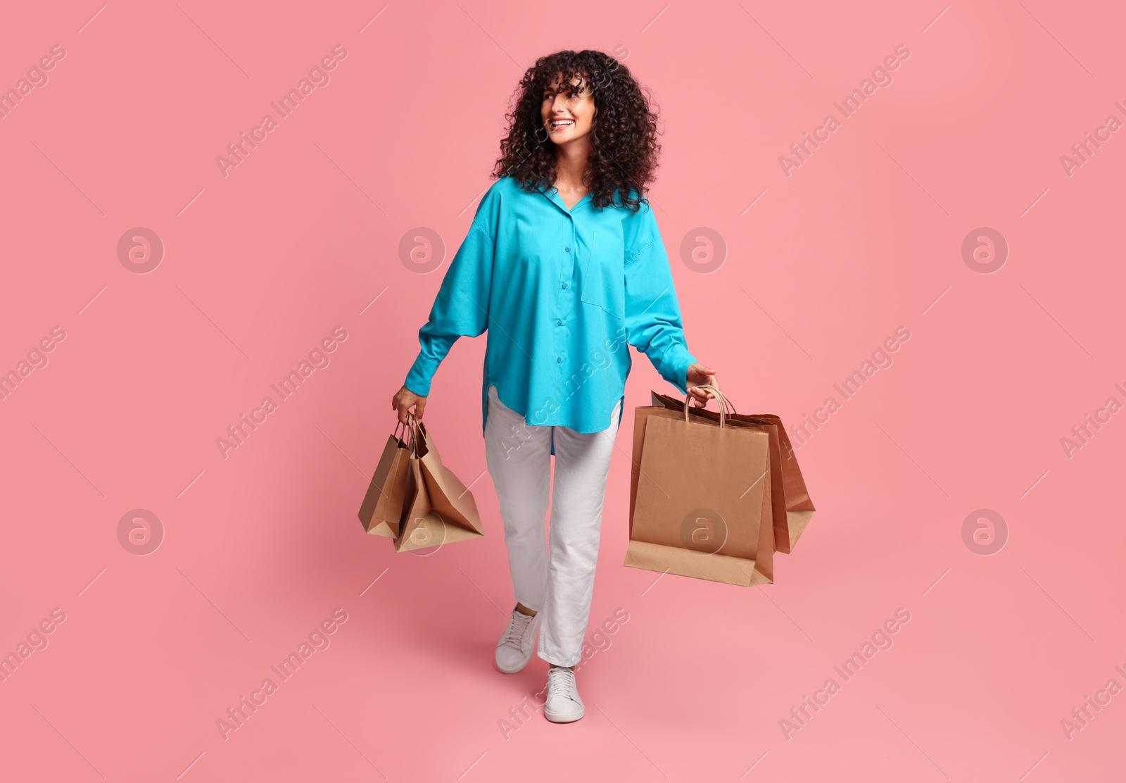 Photo of Smiling woman with shopping bags on pink background