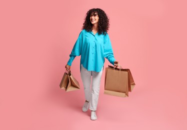 Smiling woman with shopping bags on pink background