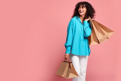 Photo of Smiling woman with shopping bags on pink background. Space for text