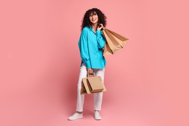 Smiling woman with shopping bags on pink background