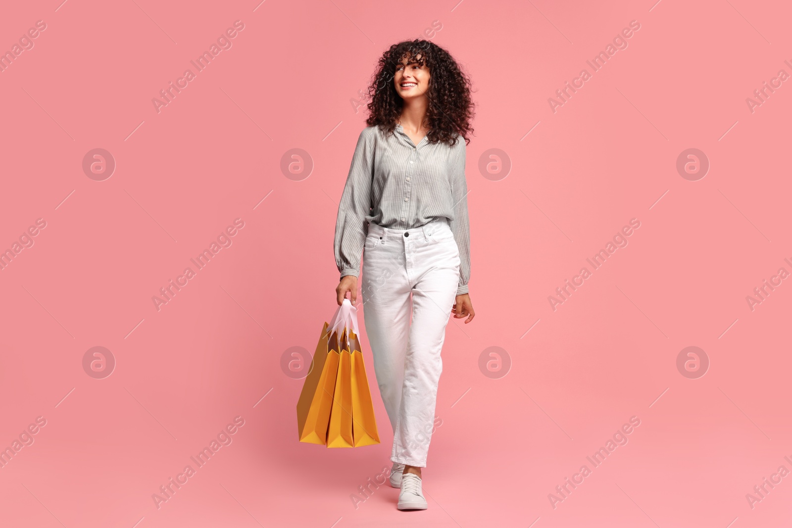 Photo of Smiling woman with colorful shopping bags on pink background