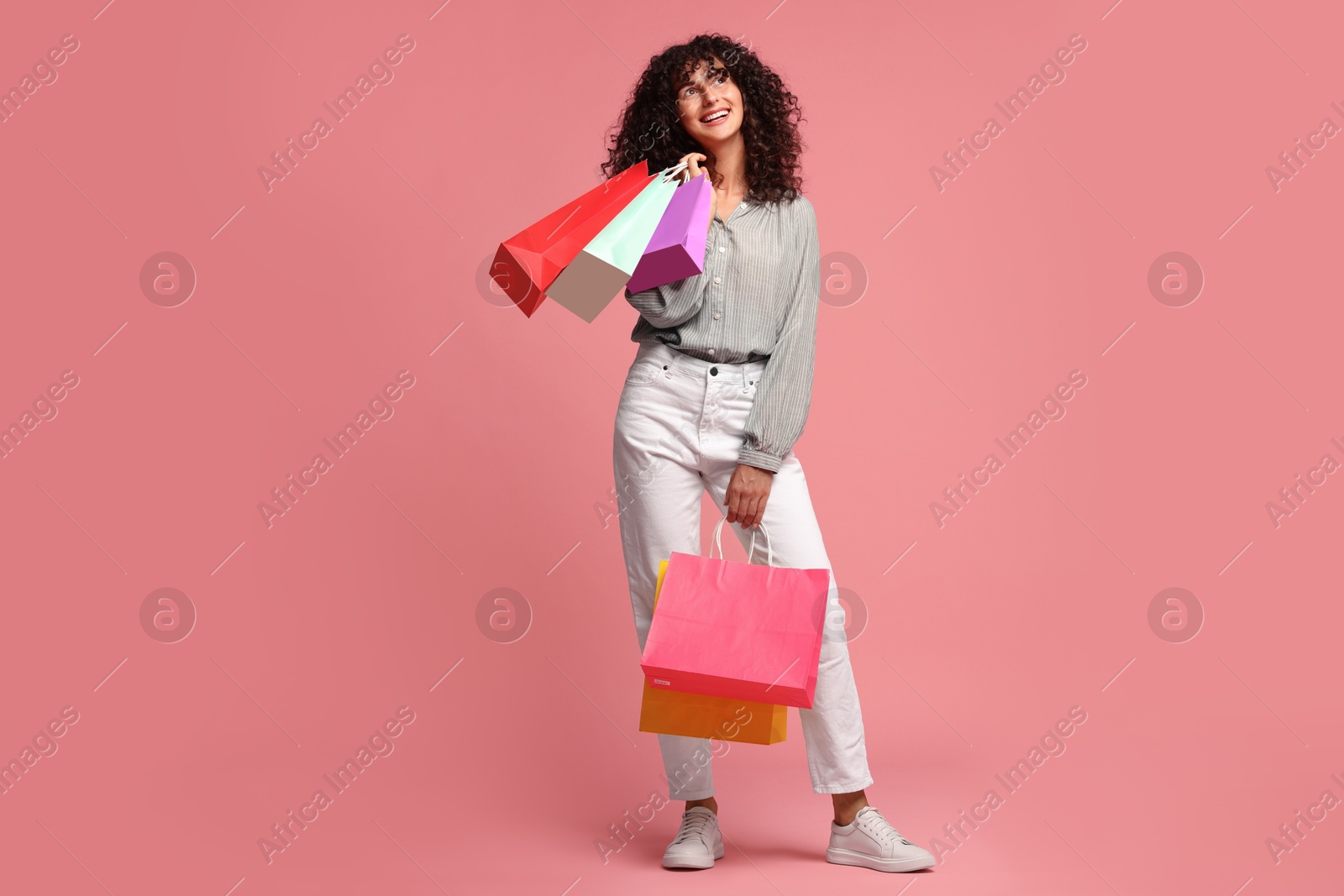 Photo of Smiling woman with colorful shopping bags on pink background