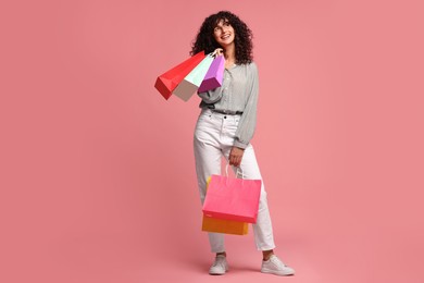 Photo of Smiling woman with colorful shopping bags on pink background