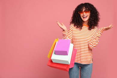 Photo of Happy woman with colorful shopping bags on pink background. Space for text