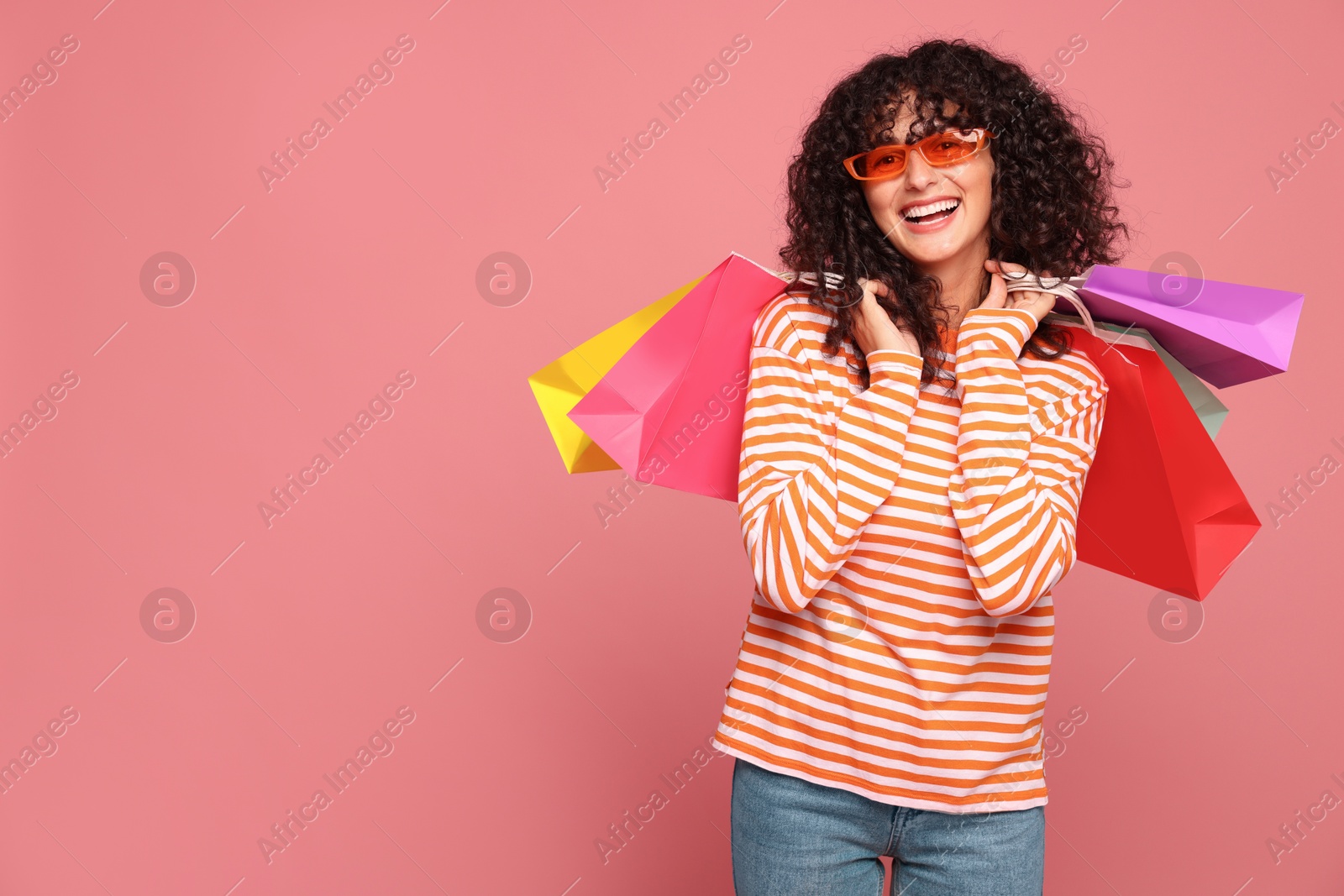 Photo of Happy woman with colorful shopping bags on pink background. Space for text