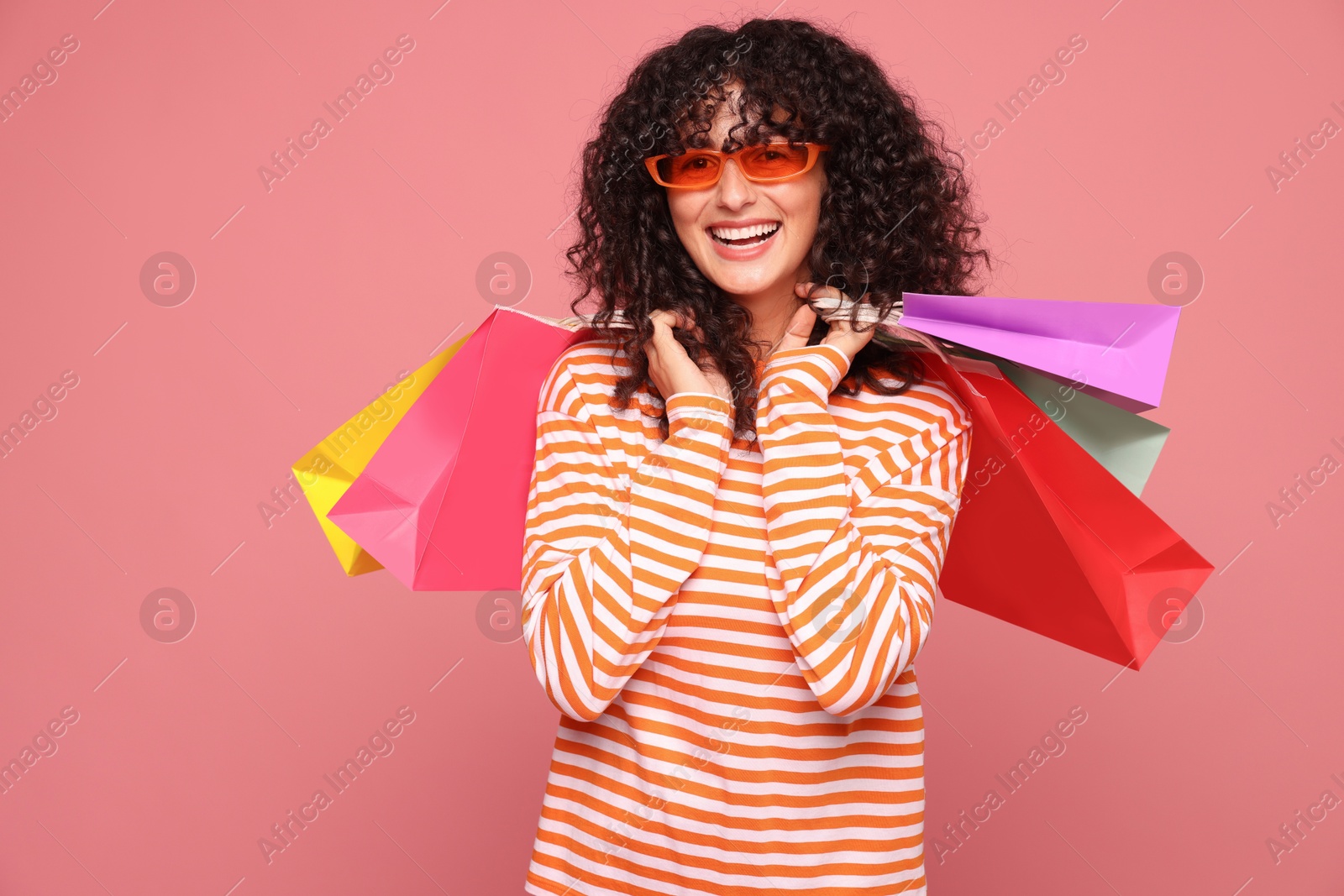 Photo of Smiling woman with colorful shopping bags on pink background