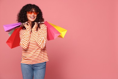 Photo of Happy woman with colorful shopping bags on pink background. Space for text