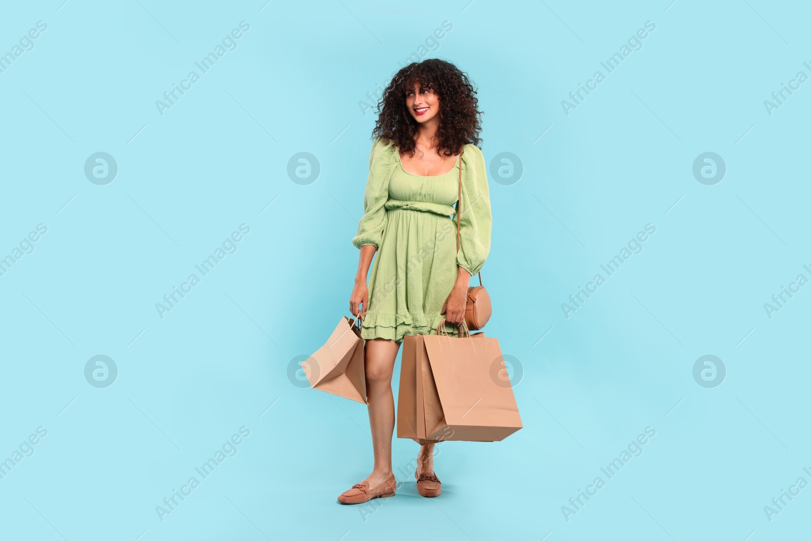 Photo of Smiling woman with shopping bags on light blue background