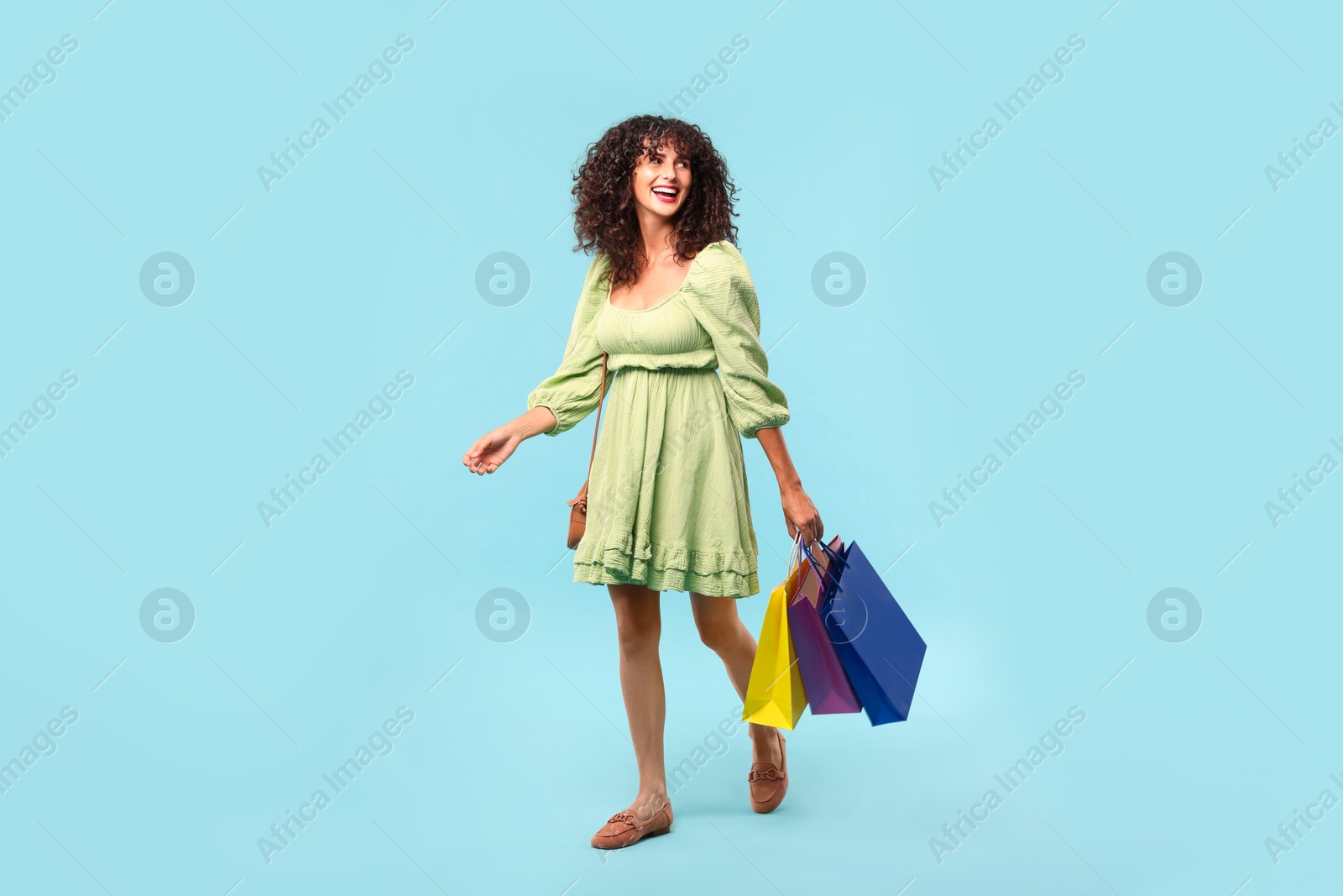 Photo of Smiling woman with colorful shopping bags on light blue background