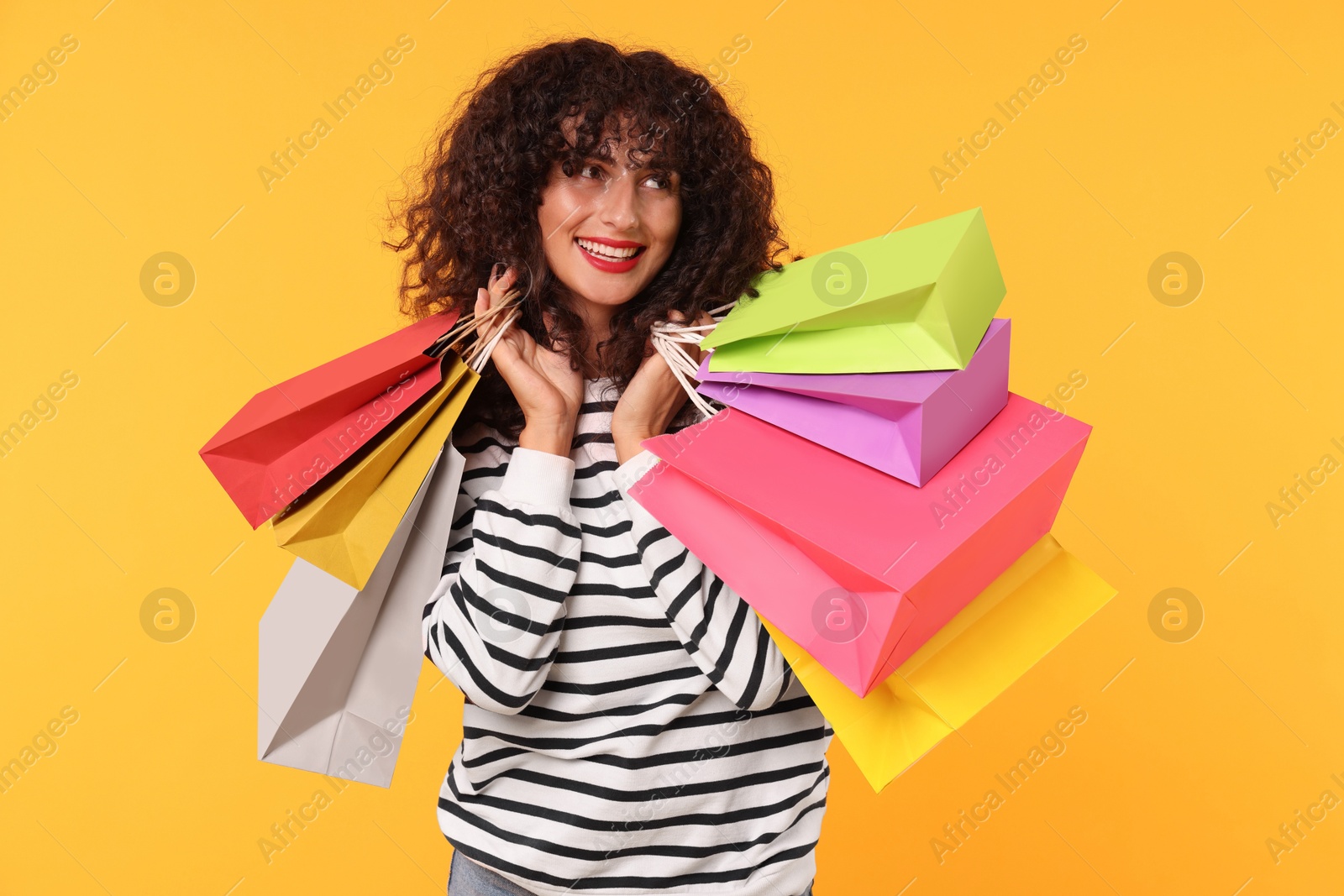 Photo of Smiling woman with colorful shopping bags on yellow background