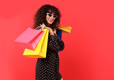 Smiling woman with colorful shopping bags on red background. Space for text