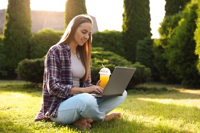 Photo of Woman using laptop on green lawn in park