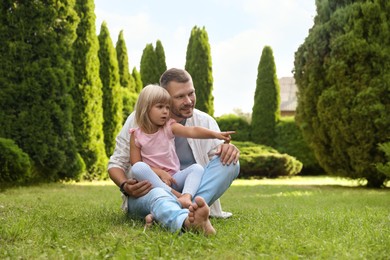 Father and his daughter spending time together on green lawn in park