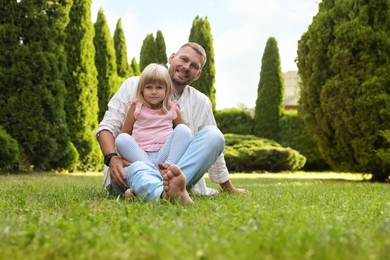 Father and his daughter spending time together on green lawn in park