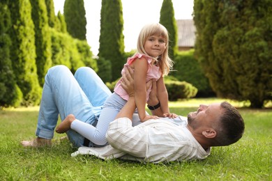 Photo of Father and his daughter spending time together on green lawn in park