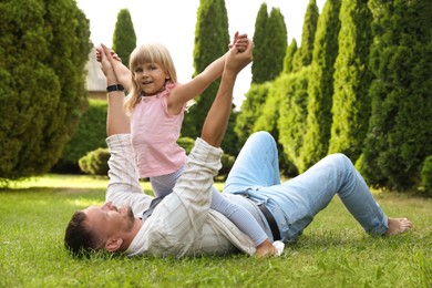 Photo of Father and his daughter spending time together on green lawn in park