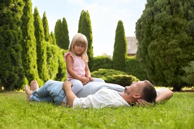 Father and his daughter spending time together on green lawn in park