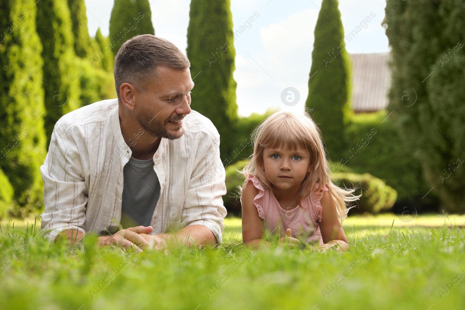 Photo of Father and his daughter spending time together on green lawn in park