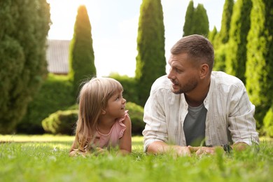 Father and his daughter spending time together on green lawn in park