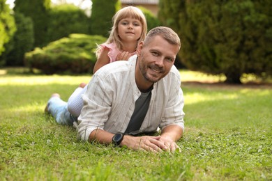 Photo of Father and his daughter spending time together on green lawn in park