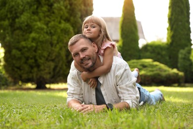 Father and his daughter spending time together on green lawn in park