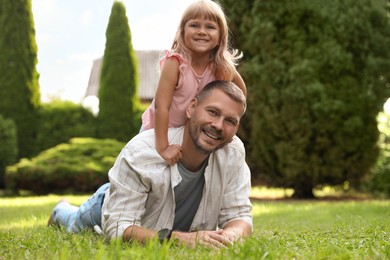 Father and his daughter spending time together on green lawn in park