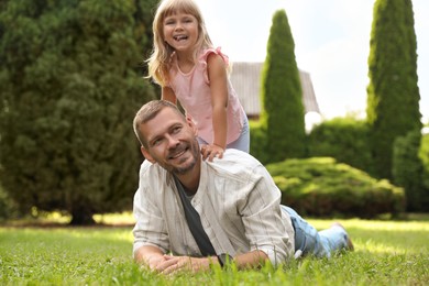 Father and his daughter spending time together on green lawn in park