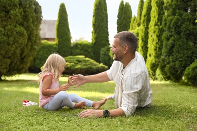 Photo of Father and his daughter spending time together on green lawn in park