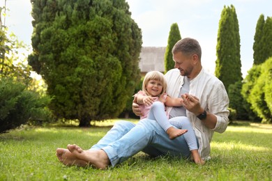 Photo of Father and his daughter spending time together on green lawn in park