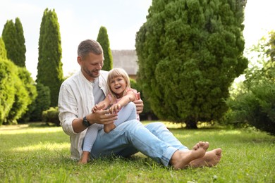 Father and his daughter spending time together on green lawn in park