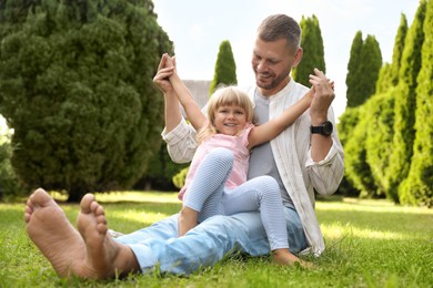 Photo of Father and his daughter spending time together on green lawn in park