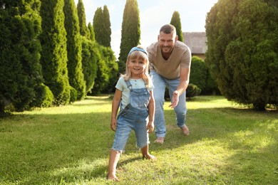 Father and his daughter spending time together on green lawn in park