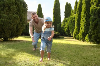 Photo of Father and his daughter spending time together on green lawn in park