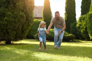 Photo of Father and his daughter spending time together on green lawn in park