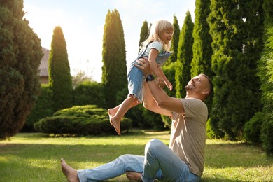 Father and his daughter spending time together on green lawn in park