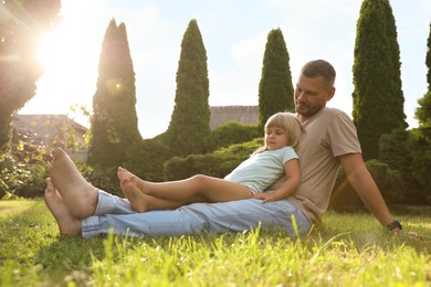 Father and his daughter spending time together on green lawn in park