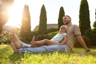 Father and his daughter spending time together on green lawn in park