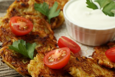 Photo of Delicious potato pancakes, sour cream, tomatoes and parsley on plate, closeup