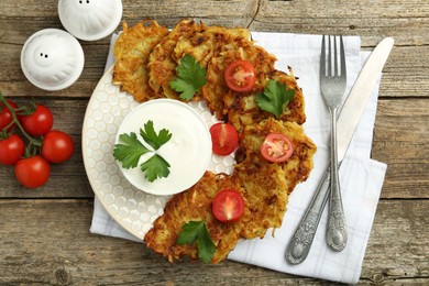 Photo of Delicious potato pancakes served on wooden table, flat lay