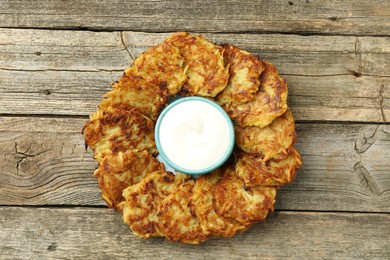 Photo of Delicious potato pancakes and sour cream on wooden table, top view