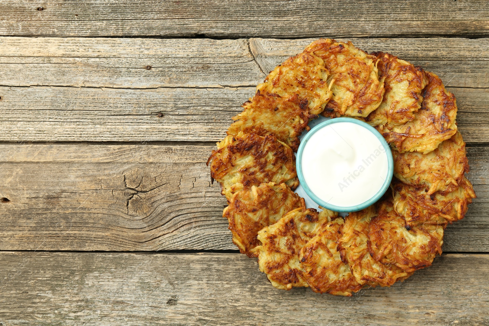 Photo of Delicious potato pancakes and sour cream on wooden table, top view. Space for text