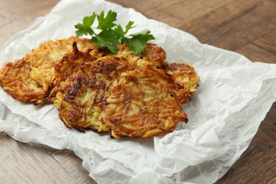 Photo of Delicious potato pancakes and parsley on wooden table, closeup