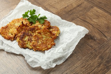 Photo of Delicious potato pancakes and parsley on wooden table, closeup