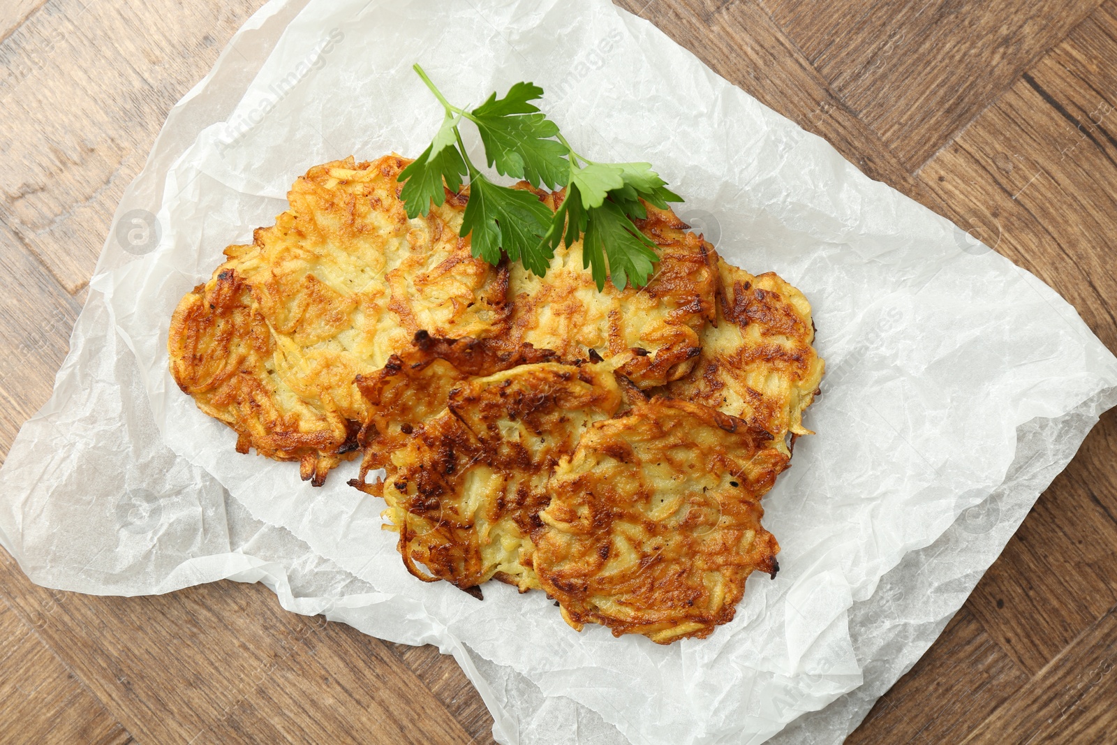 Photo of Delicious potato pancakes and parsley on wooden table, top view