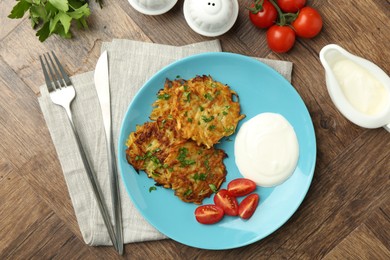 Photo of Delicious potato pancakes served on wooden table, flat lay