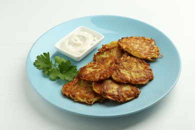 Photo of Delicious potato pancakes and sour cream on white table, closeup